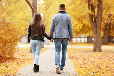 Young couple walking in park on autumn dayの写真素材