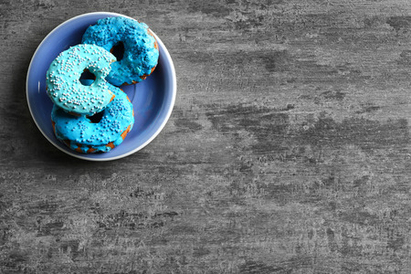 Plate with yummy colorful donuts on grey backgroundの写真素材
