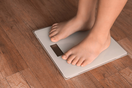 Overweight boy using scales at homeの写真素材