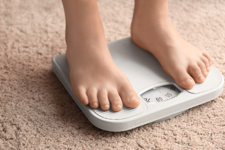 Overweight boy using scales at homeの写真素材