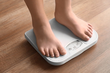 Overweight boy using scales at homeの写真素材