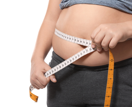 Overweight boy measuring his waist on white background, closeupの写真素材