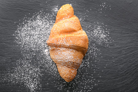 Fresh yummy croissant with sugar powder on dark backgroundの写真素材