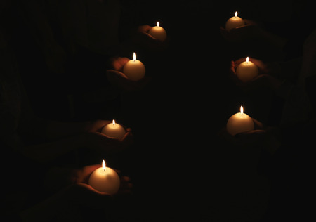 Many people with burning candles in darkness
