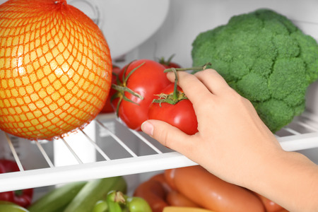 Woman taking tomatoes from refrigerator, closeupの写真素材