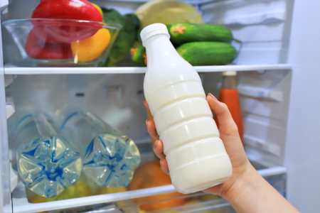 Woman taking bottle of milk from refrigerator, closeupの写真素材