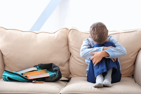 Depressed little boy on couch at homeの写真素材
