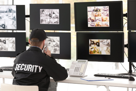 Male security guard talking by telephone in surveillance roomの写真素材