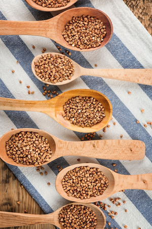 Wooden spoons with raw buckwheat on tableの写真素材