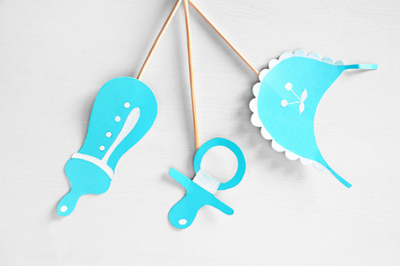 Paper decorations for baby shower party on light background, top view