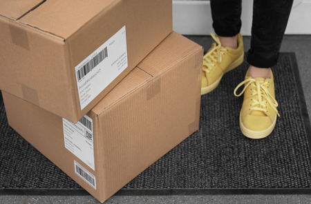 Woman standing near delivered parcels on doormat, closeupの写真素材