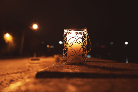Holder with burning candle at night, outdoorsの写真素材