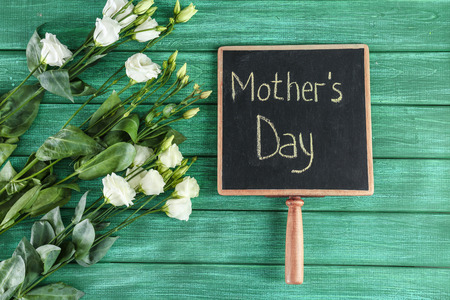 Chalkboard with phrase MOTHER'S DAY and flowers on wooden backgroundの写真素材