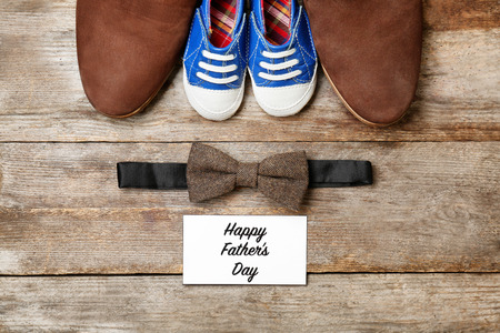 Bow tie, big and small shoes on wooden background. Father's day compositionの写真素材