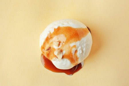 Ice cream ball with caramel sauce on color backgroundの写真素材