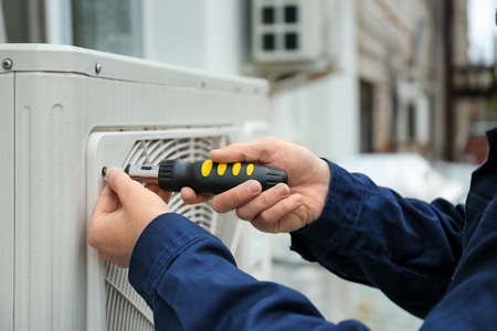 Male technician fixing air conditioner outdoorsの写真素材