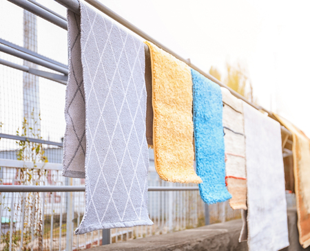 Different carpets hanging on rack outdoorsの写真素材