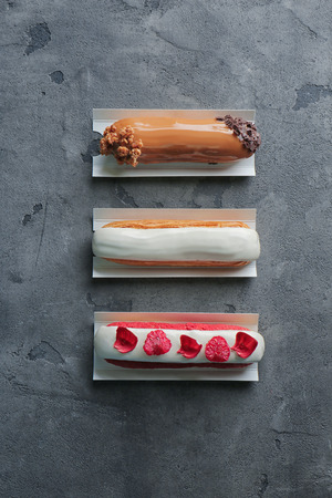 Various tasty eclairs on grunge background