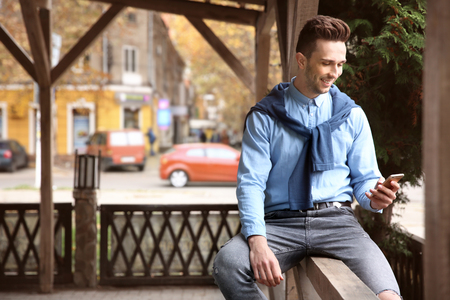 Portrait of young hipster man with phone outdoorsの写真素材