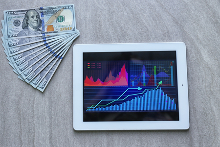 Tablet with stock data and money on tableの写真素材