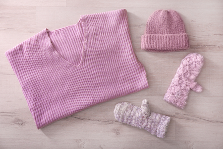 Warm knitted clothes on wooden background. Seasonal female wardrobeの写真素材