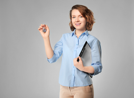 Beautiful real estate agent with key on grey backgroundの写真素材