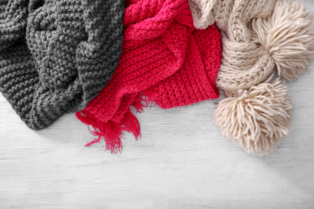 Color knitted scarves on wooden background. Seasonal female wardrobeの写真素材