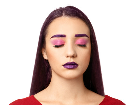 Young woman with dyed eyebrows and creative makeup on white background