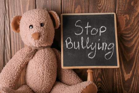 Chalkboard with text STOP BULLYING and toy on wooden backgroundの写真素材