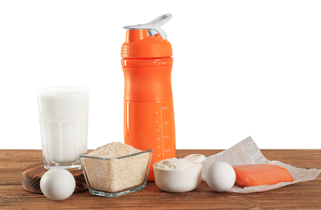 Protein shake in bottle, scoop with powder and products on tableの写真素材