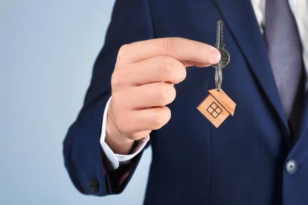 Real estate agent holding key to new house on grey backgroundの写真素材