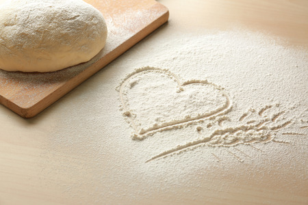 Composition with raw dough and heart drawn on flourの写真素材