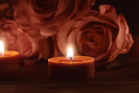 Beautiful burning candles and roses in darknessの写真素材