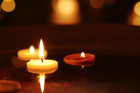 Small burning candles floating in plate with water, closeupの写真素材