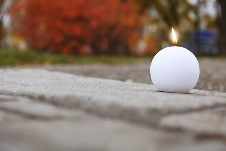 Burning candle on ground outdoorsの写真素材