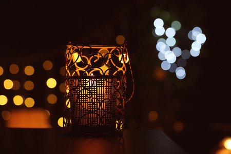Beautiful holder with burning candle on dark blurred background