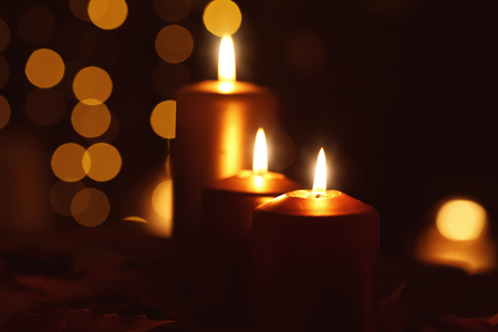 Beautiful burning candles in darkness against defocused lightsの写真素材