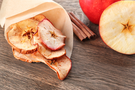 Tasty apple chips wrapped in paper on wooden tableの写真素材