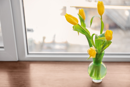 Vase with beautiful flowers on window sillの写真素材