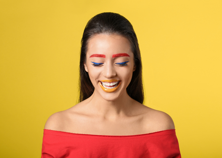 Young woman with dyed eyebrows and creative makeup on color backgroundの写真素材