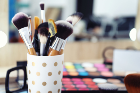Different brushes with cosmetics of professional makeup artist on dressing tableの写真素材