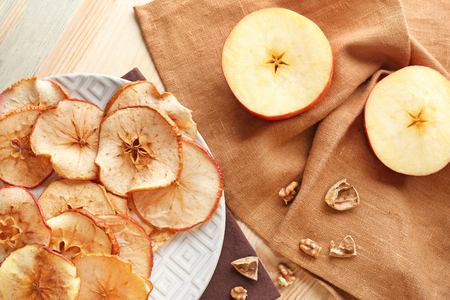 Plate with tasty apple chips and fresh fruit on wooden tableの写真素材