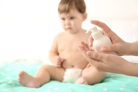 Woman holding baby body cream against blurred backgroundの写真素材