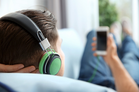 Relaxed young man listening to music at homeの写真素材
