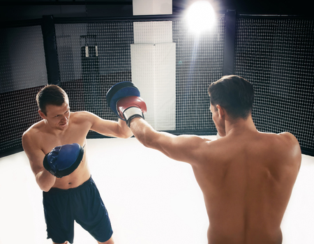 Young boxer training in gym with personal coach