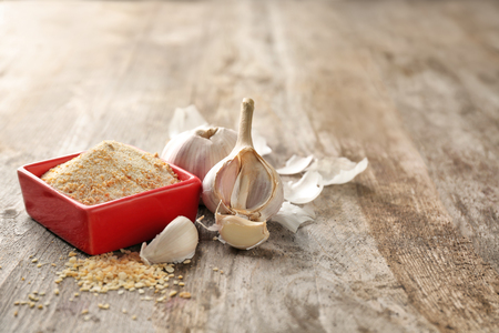 Bowl with dried garlic powder on wooden backgroundの写真素材