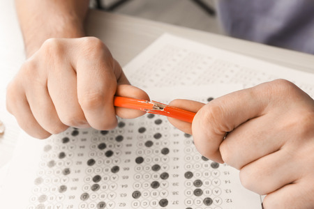 Nervous student breaking pencil while passing exam, closeup