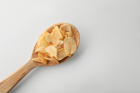 Dried garlic flakes in spoon on white backgroundの写真素材