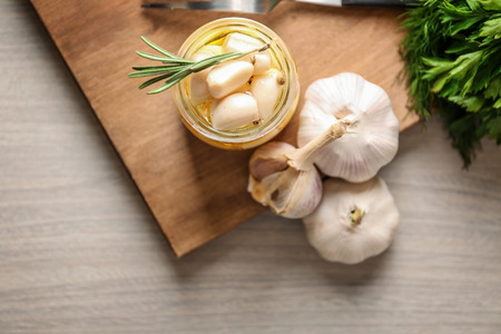 Preserved garlic in glass jar on wooden boardの写真素材