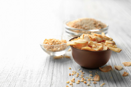 Bowl with dried garlic flakes on wooden backgroundの写真素材